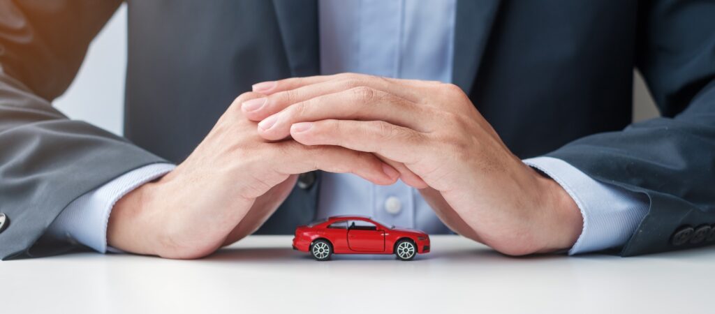 Businessman hand cover or protection red car toy on table. Car insurance, warranty, repair